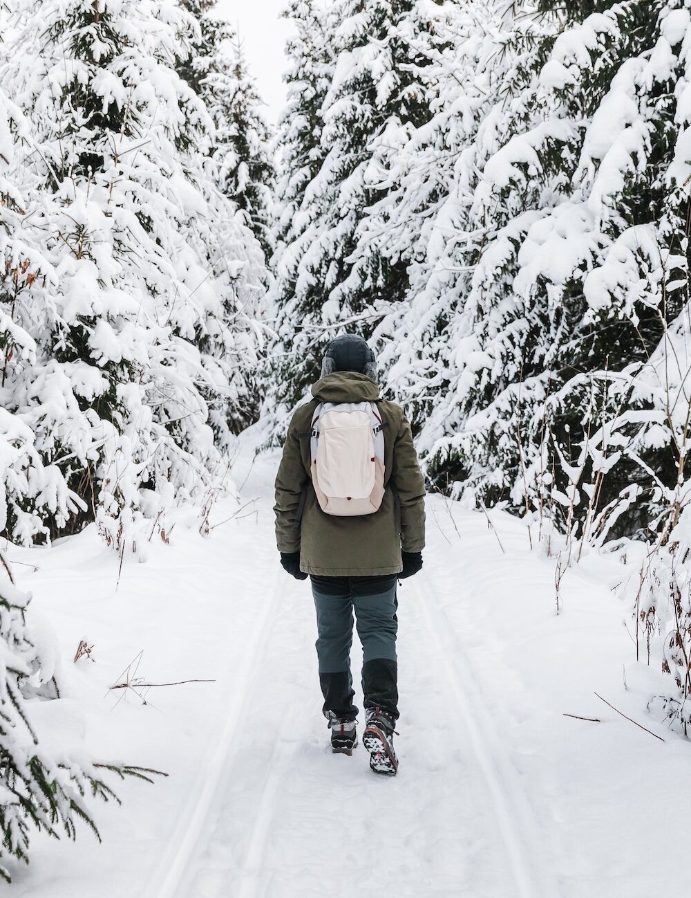 Man with backpack walking on snow covered forest. Beautiful winter time. Back view.